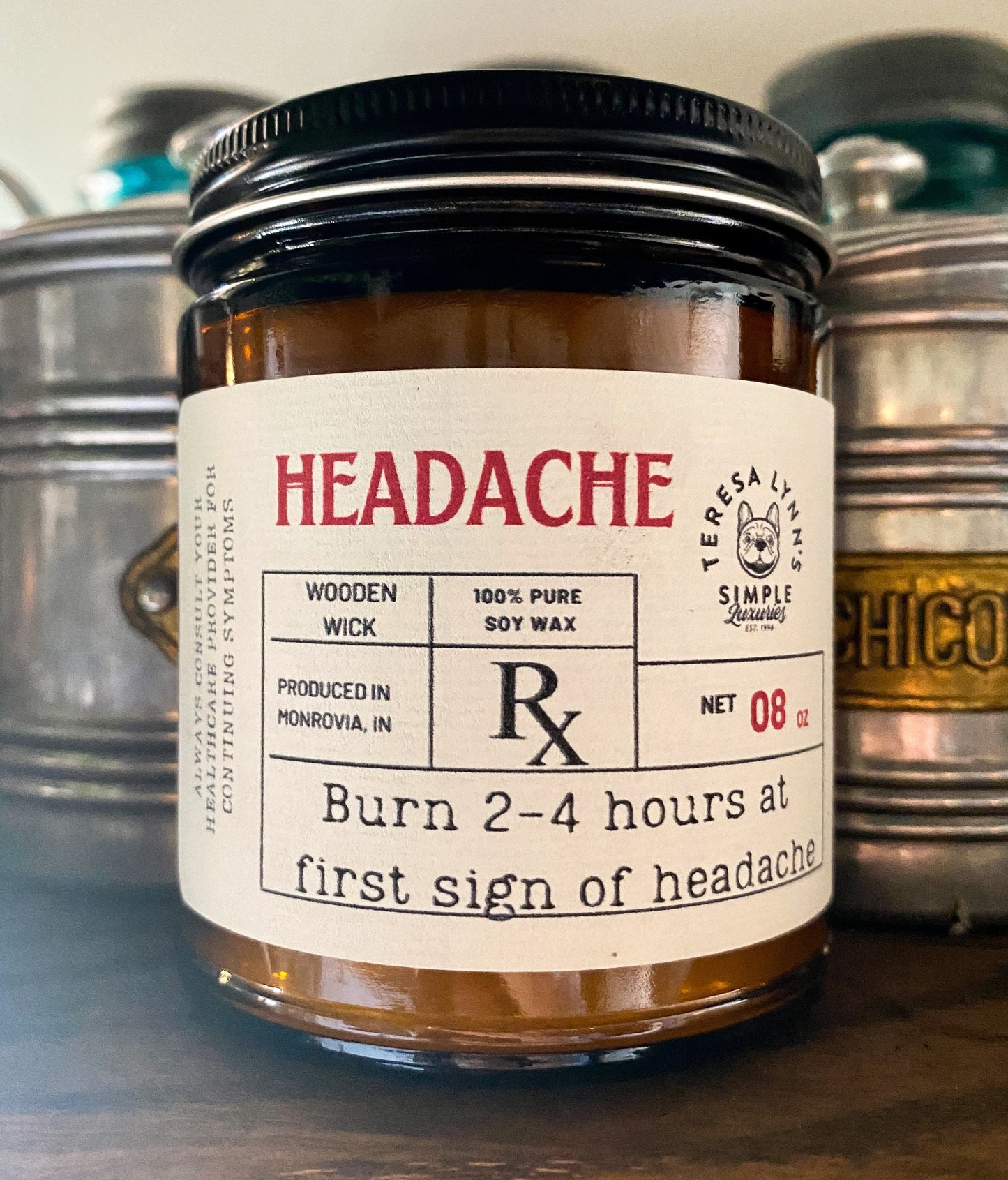 a 9oz brown glass apothecary style candle jar with a black lid. The label is designed to look like a vintage prescription label with the word Headache at the top in red antique font.