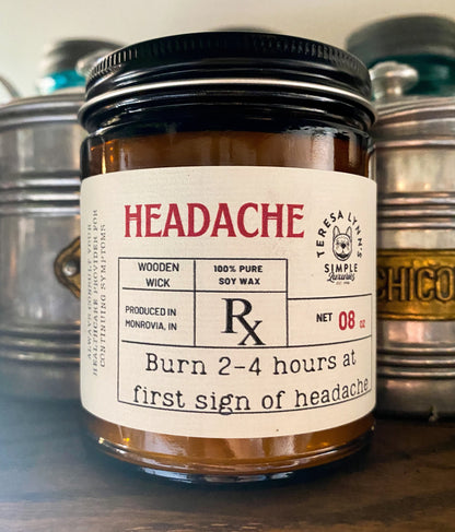 a 9oz brown glass apothecary style candle jar with a black lid.  The label is designed to look like a vintage prescription label with the word Headache at the top in red antique font.